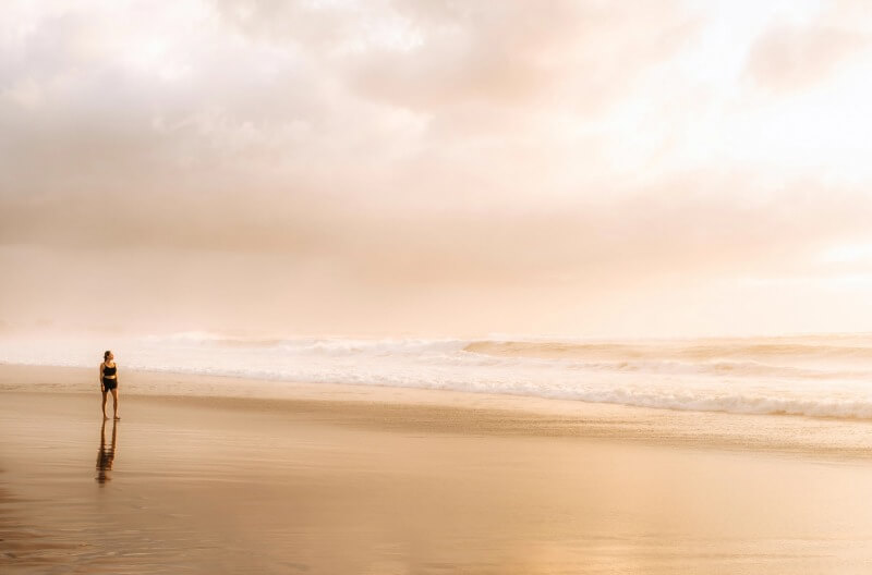 Person walking along a beach at sunset