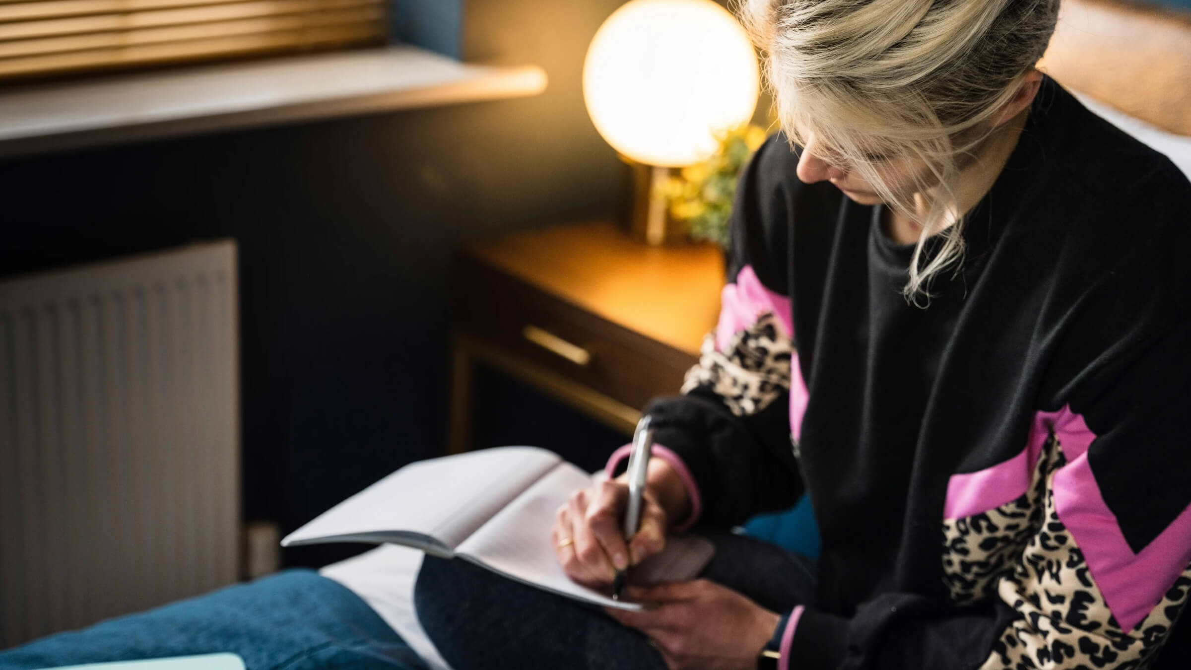 Person writing in a notebook during a quiet moment of reflection indoors