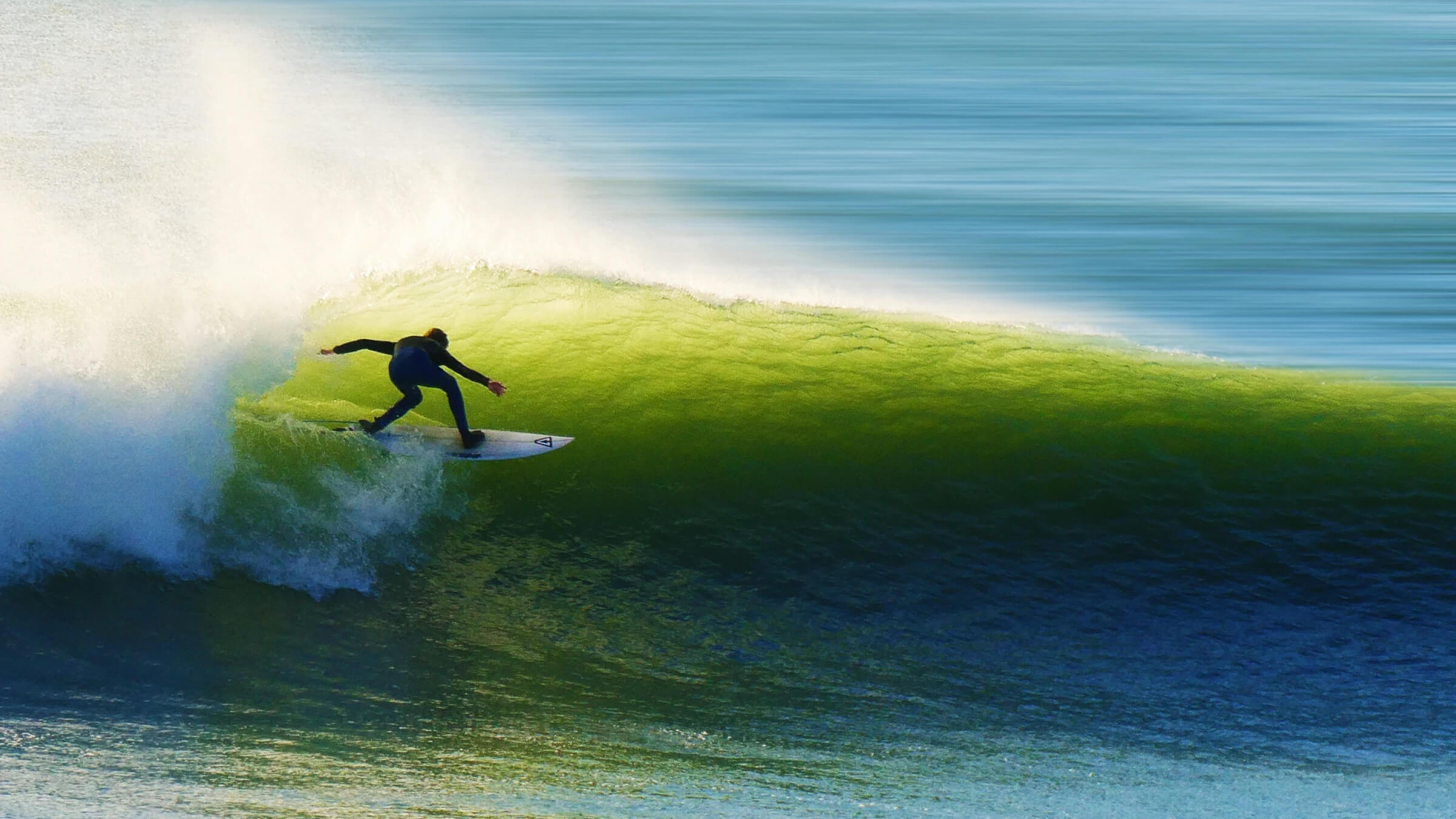 Surfer riding inside a curling green wave along the ocean coast